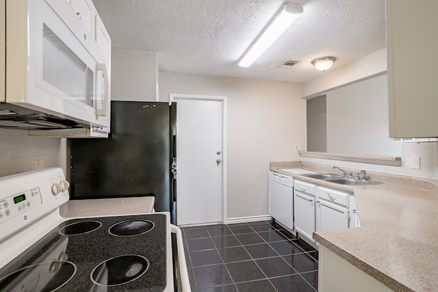 kitchen with visible vents, dark tile patterned floors, light countertops, white appliances, and a sink