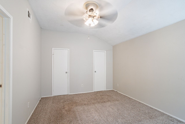 unfurnished bedroom featuring lofted ceiling, carpet, visible vents, and ceiling fan