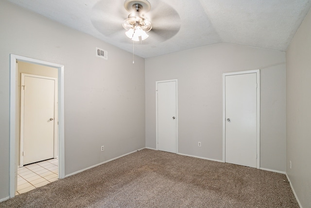 unfurnished bedroom with visible vents, baseboards, lofted ceiling, light carpet, and a textured ceiling