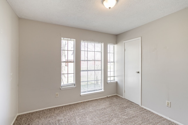 carpeted spare room featuring plenty of natural light and a textured ceiling