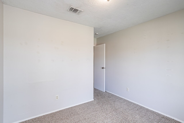 empty room with baseboards, visible vents, a textured ceiling, and carpet