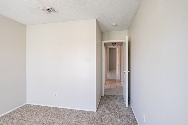 carpeted empty room with baseboards, visible vents, and a textured ceiling