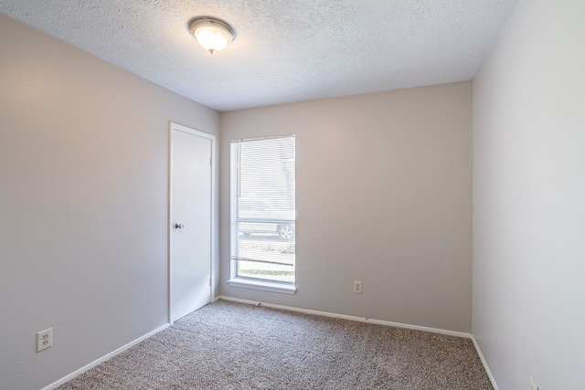 carpeted spare room with baseboards and a textured ceiling