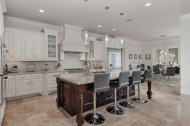 kitchen with visible vents, stainless steel built in refrigerator, ornamental molding, decorative backsplash, and custom exhaust hood