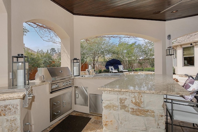 view of patio with outdoor wet bar, exterior kitchen, fence, and grilling area