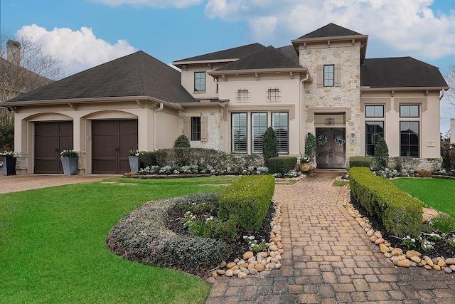 view of front of house with a front lawn, stucco siding, decorative driveway, a garage, and stone siding