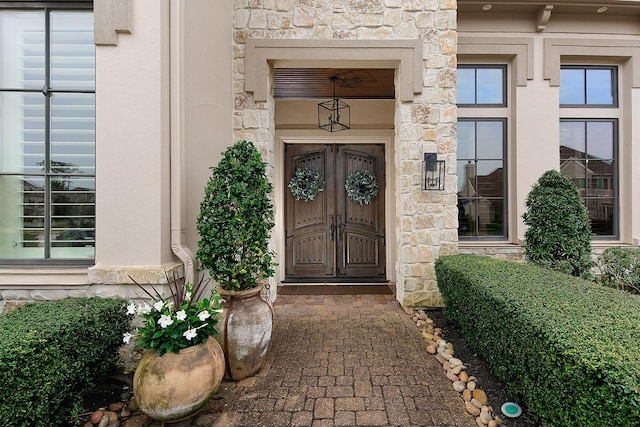 property entrance featuring stucco siding and stone siding