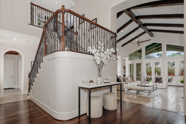 stairs with arched walkways, beamed ceiling, french doors, and high vaulted ceiling