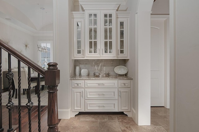 bar with stairway, lofted ceiling, stone tile flooring, decorative backsplash, and crown molding