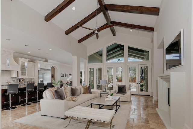 living room featuring beam ceiling, high vaulted ceiling, stone tile floors, french doors, and arched walkways