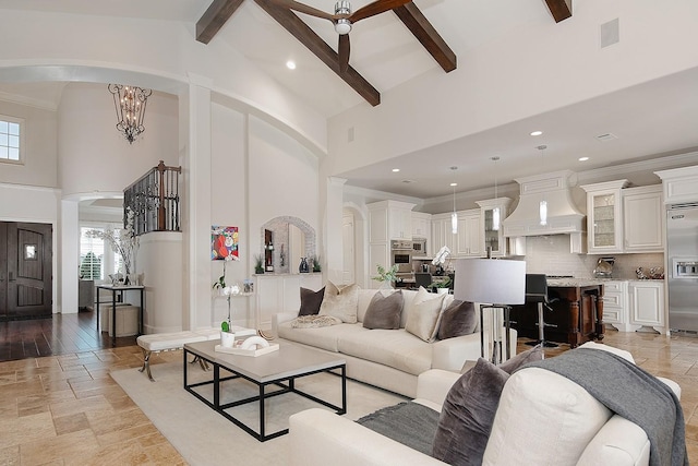 living area with beamed ceiling, high vaulted ceiling, stone tile floors, and stairs