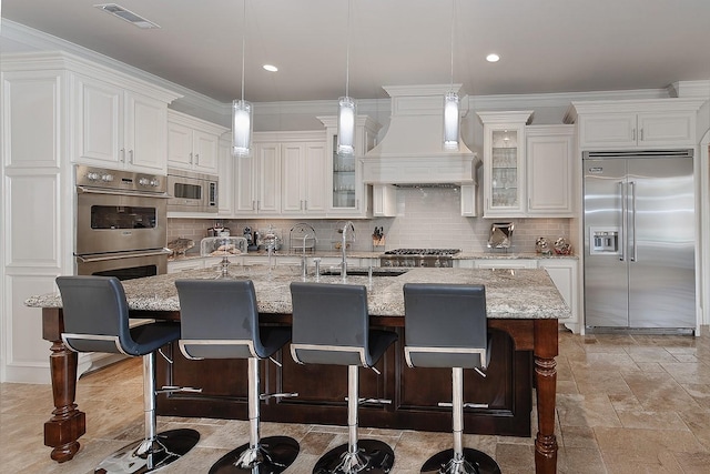 kitchen featuring visible vents, a sink, tasteful backsplash, built in appliances, and custom exhaust hood