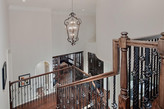 staircase with a chandelier, ornamental molding, recessed lighting, a high ceiling, and wood finished floors