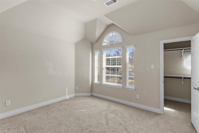 unfurnished bedroom with vaulted ceiling, multiple windows, visible vents, and carpet floors