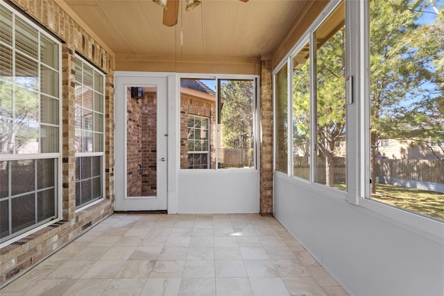 unfurnished sunroom with wood ceiling and a ceiling fan