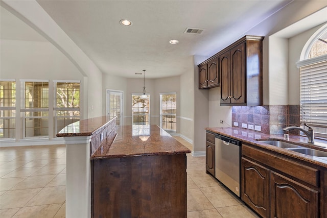 kitchen featuring visible vents, dishwasher, light tile patterned floors, dark stone countertops, and a sink