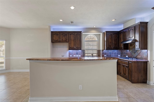 kitchen featuring a healthy amount of sunlight, stainless steel gas cooktop, under cabinet range hood, and a sink