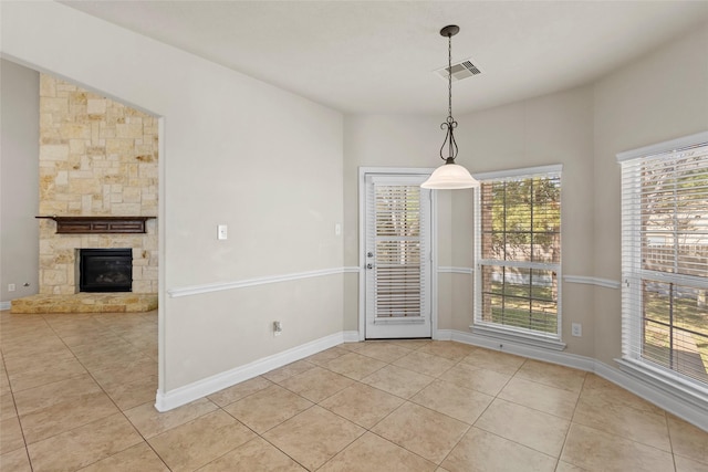 unfurnished dining area featuring light tile patterned flooring, baseboards, visible vents, and plenty of natural light