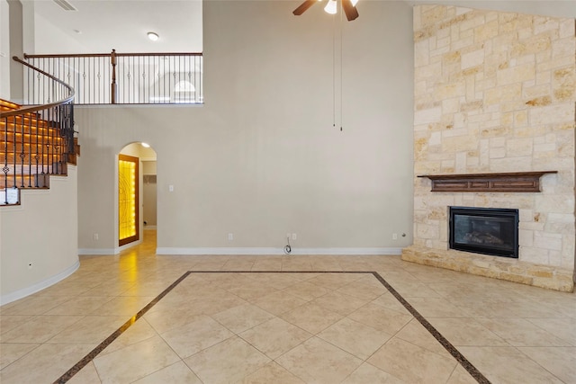 unfurnished living room with ceiling fan, a fireplace, stairs, and baseboards