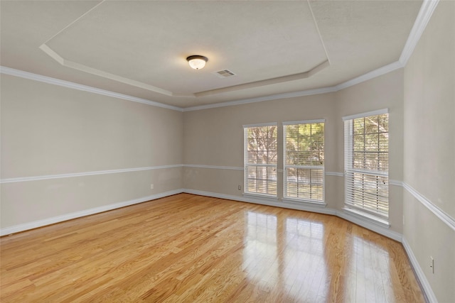 unfurnished room featuring visible vents, baseboards, a tray ceiling, and wood finished floors