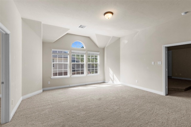 carpeted empty room with visible vents, baseboards, and vaulted ceiling