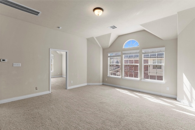 carpeted spare room featuring lofted ceiling, baseboards, and visible vents