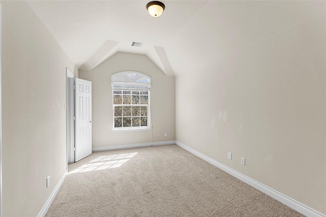 spare room with lofted ceiling, baseboards, visible vents, and light carpet