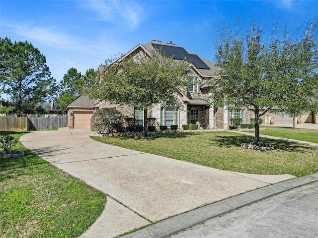 view of front of house featuring roof mounted solar panels, fence, concrete driveway, an attached garage, and a front yard