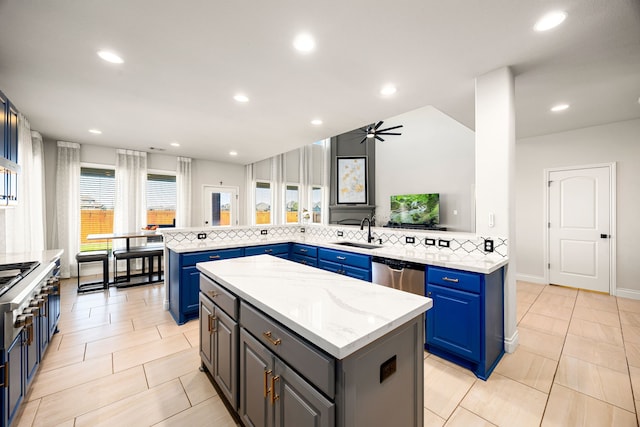 kitchen with a sink, dishwasher, blue cabinets, and a kitchen island