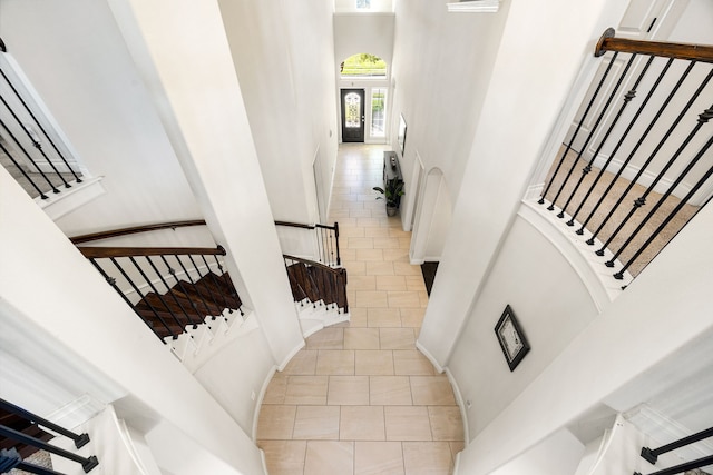 staircase featuring tile patterned flooring and a high ceiling