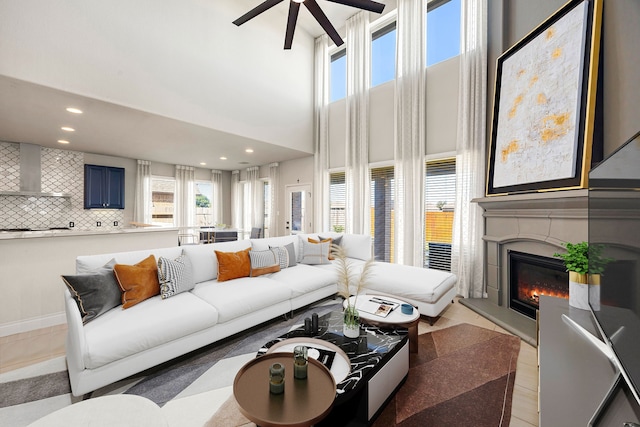 living room featuring a high end fireplace, a high ceiling, recessed lighting, and a wealth of natural light