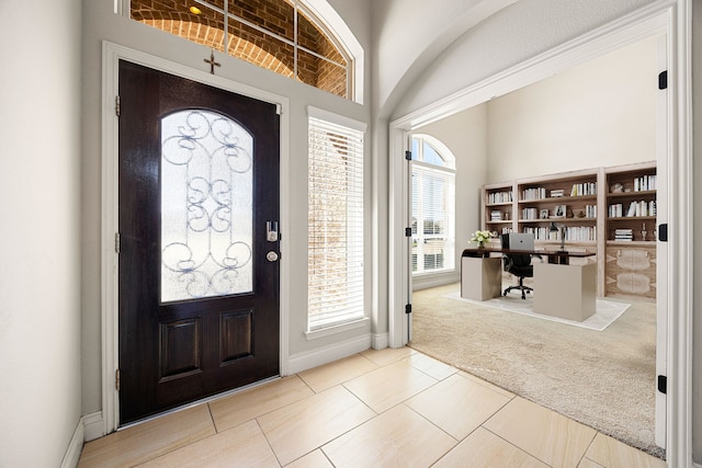 carpeted foyer with tile patterned floors and baseboards