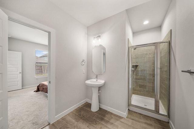 ensuite bathroom with wood finished floors, baseboards, and a stall shower