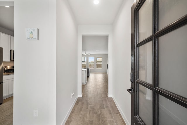 hall featuring light wood-type flooring and baseboards