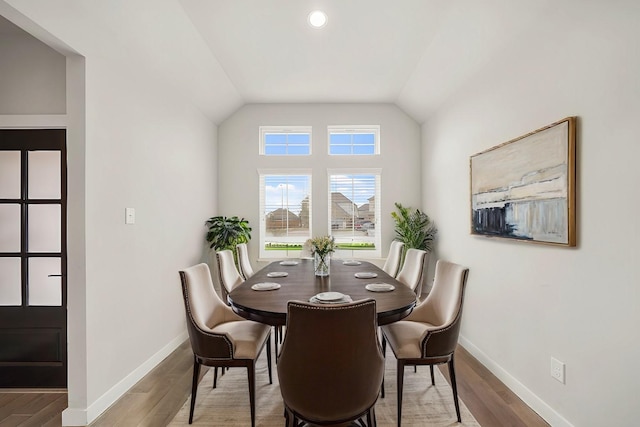 dining room featuring lofted ceiling, wood finished floors, and baseboards