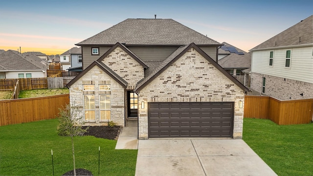 french provincial home featuring stone siding, a lawn, driveway, and a shingled roof