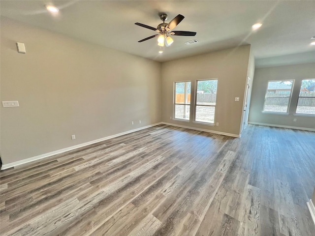 spare room with baseboards, wood finished floors, visible vents, and a healthy amount of sunlight