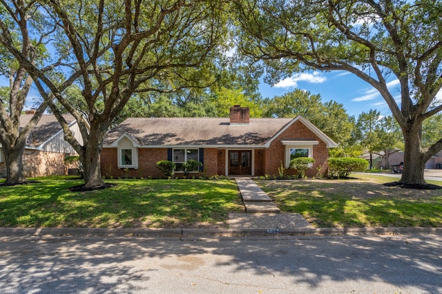 ranch-style home featuring a front lawn, french doors, brick siding, and a chimney