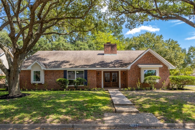 ranch-style house featuring a front yard, roof with shingles, a chimney, french doors, and brick siding