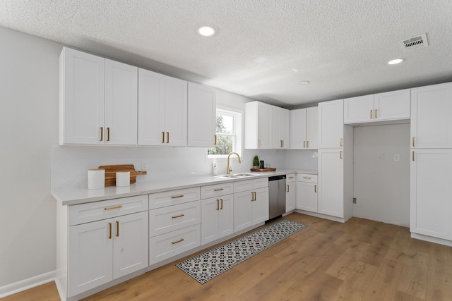 kitchen featuring stainless steel dishwasher, light wood-type flooring, visible vents, and a sink