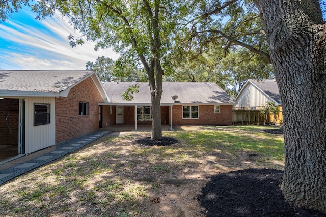 rear view of house with brick siding, a patio, and fence