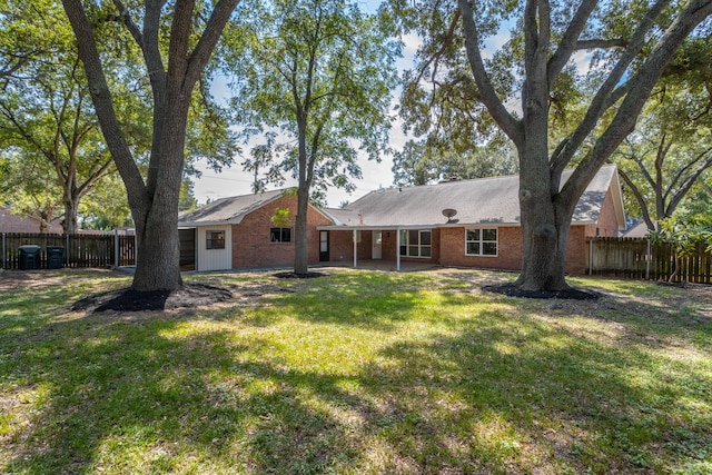 back of house featuring brick siding, a patio area, a yard, and fence