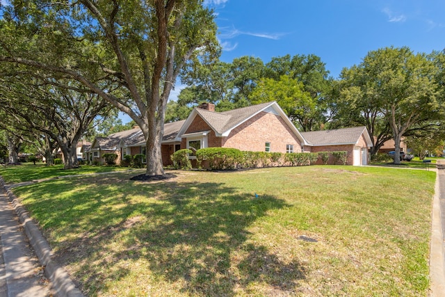 single story home with brick siding, an attached garage, a chimney, and a front lawn