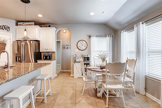 dining area featuring light tile patterned flooring, recessed lighting, arched walkways, and vaulted ceiling