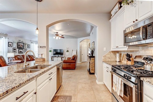 kitchen with a ceiling fan, open floor plan, appliances with stainless steel finishes, and a sink