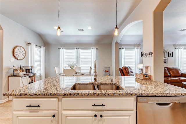 kitchen with a sink, arched walkways, stainless steel dishwasher, and light stone counters