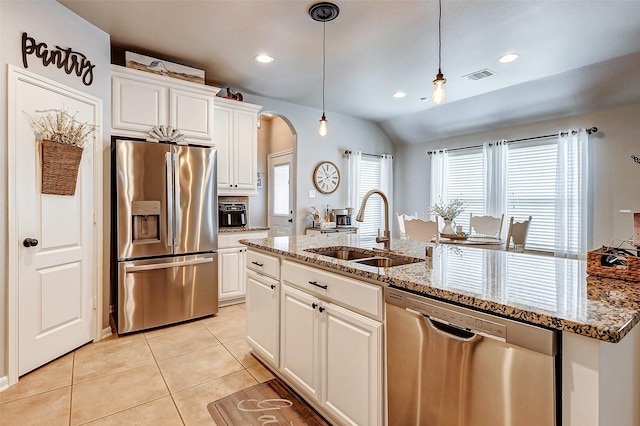 kitchen with visible vents, light tile patterned flooring, arched walkways, a sink, and appliances with stainless steel finishes