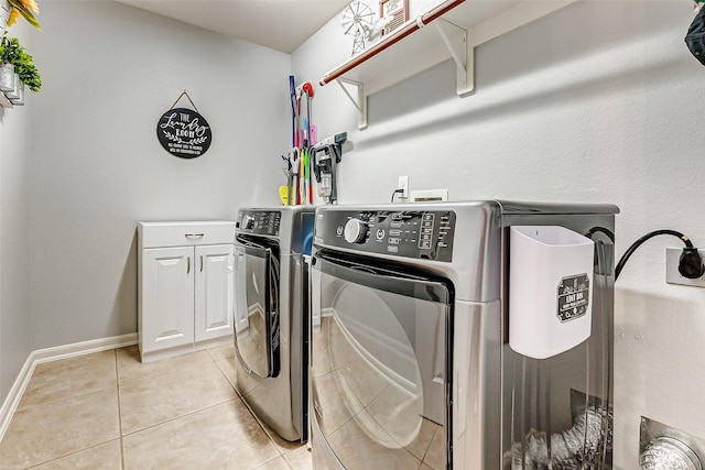 washroom featuring light tile patterned flooring, cabinet space, washer and dryer, and baseboards