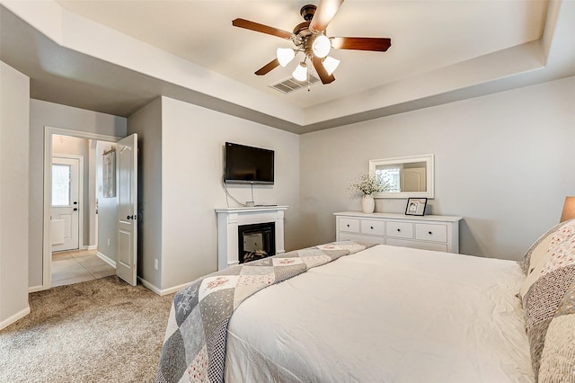 bedroom featuring visible vents, baseboards, carpet, a fireplace, and a raised ceiling