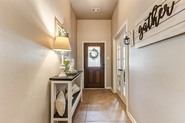 entryway featuring light tile patterned floors, baseboards, and visible vents